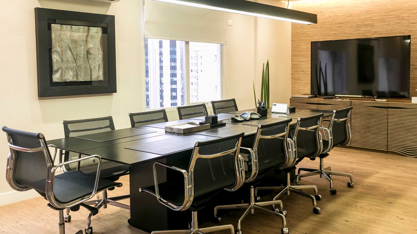 Sala de reuniões do escritório, com mesa preta e vista da cidade